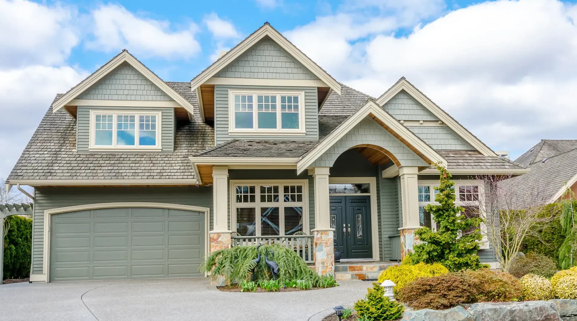 A light green house with cream-colored trim and black front door.
